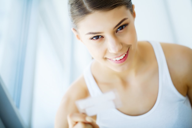 Foto sbiancamento dei denti. striscia d'imbiancatura della bella tenuta sorridente della donna. immagine ad alta risoluzione