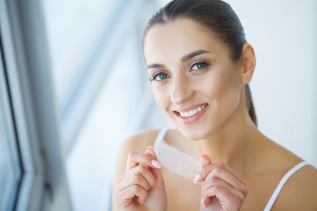 Teeth Whitening. Beautiful Smiling Woman Holding Whitening Strip.  Image