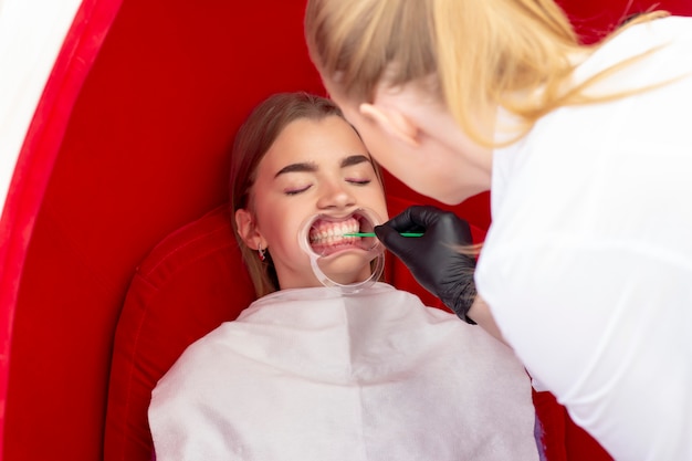 Photo teeth whitening procedure the doctor applies the drug to patient teeth