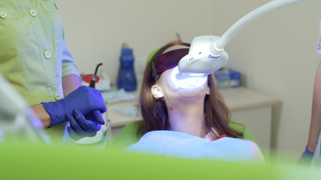 Photo teeth whitening with ultraviolet lamp patient at bleaching teeth procedure