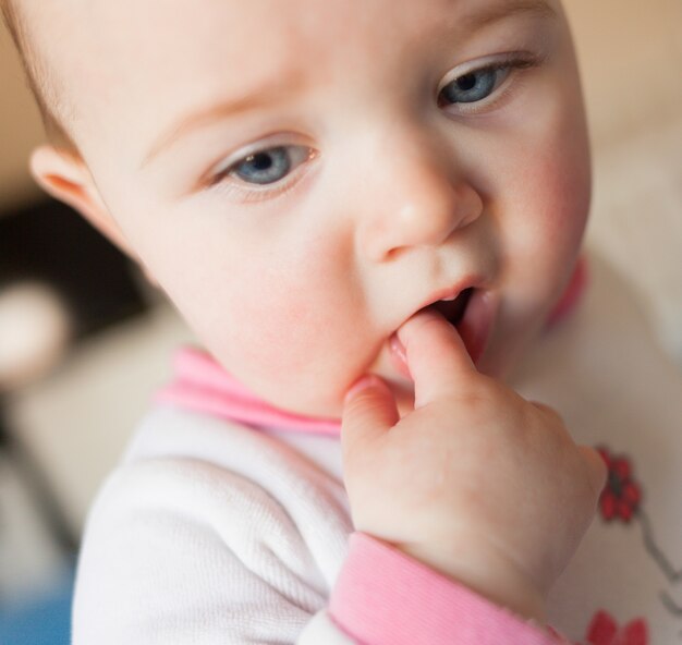 Concetto di dentizione. bambina con il dito in bocca.