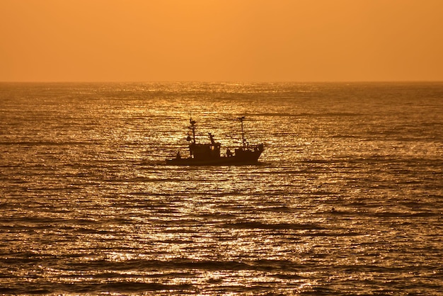 Tegenlichtbeeld van een silhouetboot in de oceaan