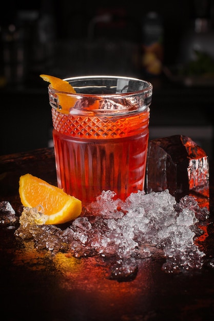 Tegroni cocktaildrank met fruit en ijsblokjes op zwarte achtergrond