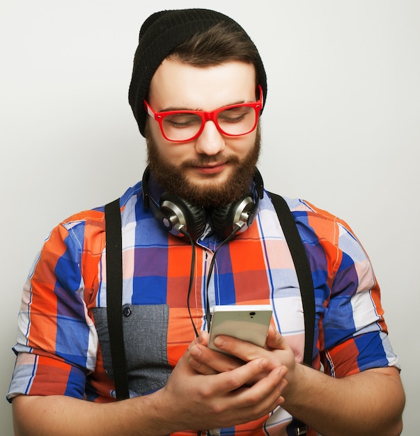 Tehnology, internet, emotionele en mensen concept: jonge, bebaarde man met mobiel over grijze achtergrond. Hipster stijl. Speciale modieuze toning.