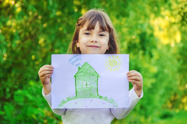 Tekening van een groen huis in de handen van een kind.