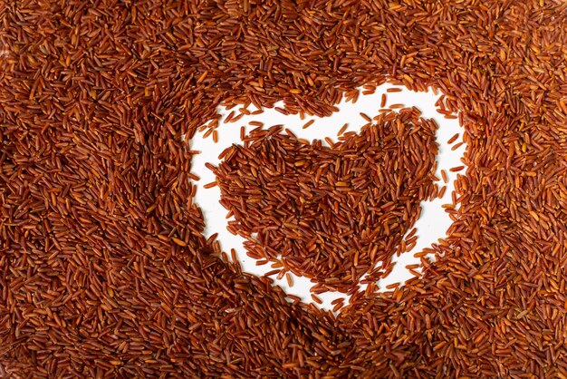Tekening van het hart op de achtergrond van bruine rijst Verspreide bruine lange rijst met hartpatroon