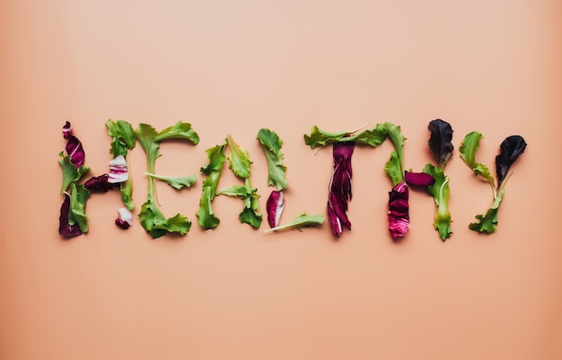 Foto tekst gezond met groene en paarse salade bladeren mix op beige achtergrond. hoge kwaliteit foto