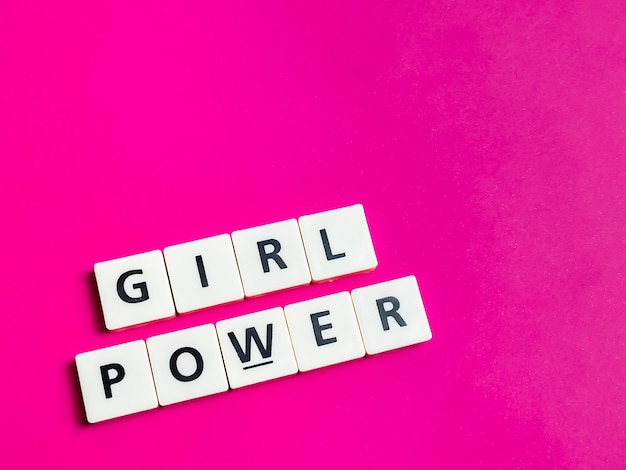 Foto tekst girl power gemaakt van vierkante lettertegels tegen felroze achtergrond.