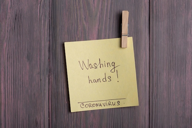 Tekst Handen wassen Coronavirus op plakbriefje dat met een wasknijper op houten achtergrond hangt - gezondheidszorg en medisch concept