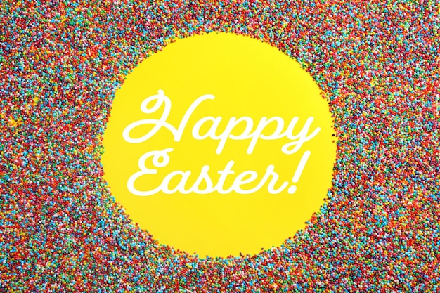 Tekst Happy Easter en frame van kleurrijke hagelslag op gele achtergrond bovenaanzicht Suikerwerk decor
