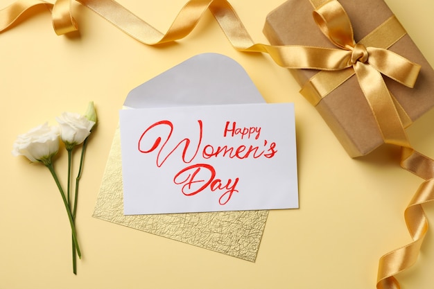 Tekst happy women's day, rozen, envelop en geschenkdoos op beige achtergrond