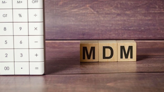 Tekst MDM als MOBILE DEVICE MANAGEMENT op houten blokken en rekenmachine