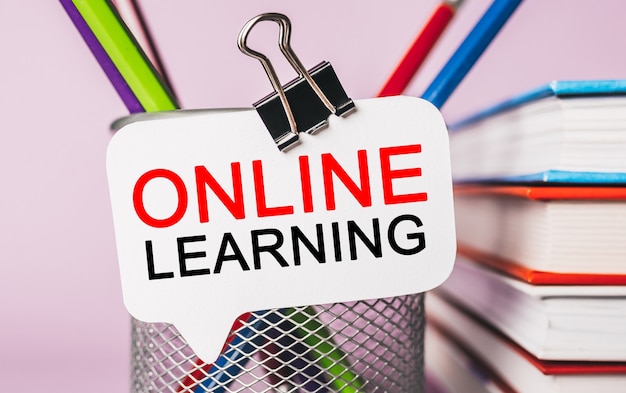 Tekst online leren op een witte sticker met de achtergrond van kantoorbenodigdheden. Plat op concept voor zaken, financiën en ontwikkeling