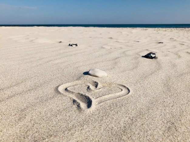 Foto tekst op zand op het strand tegen de lucht