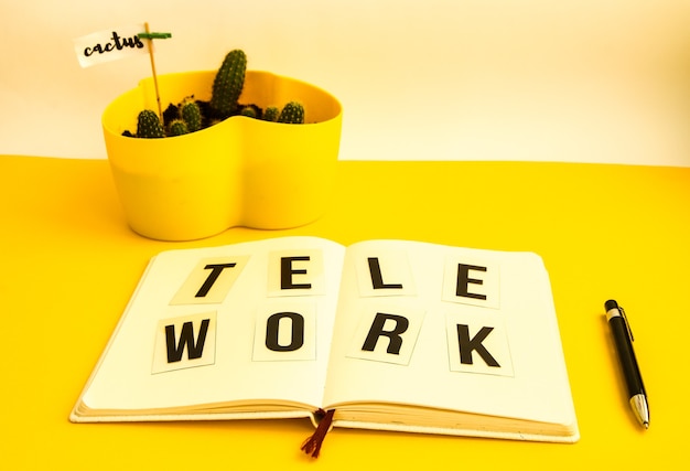 Tekst TELEWORK met notitieboekje en pen, cactus, werk vanuit huis