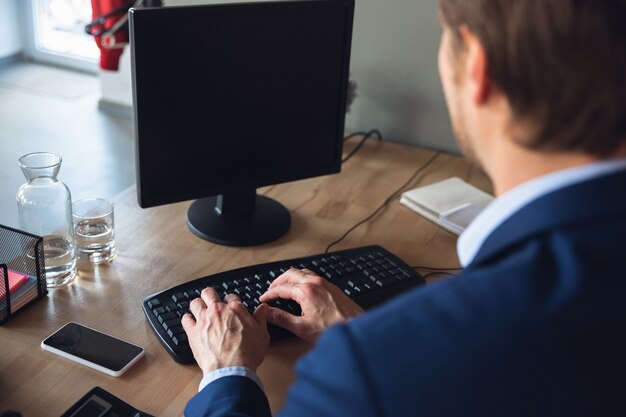 Tekst typen, werken, attent reageren. Jonge man, manager die na quarantaine weer aan het werk gaat in zijn kantoor, voelt zich gelukkig en geïnspireerd. Terugkomen in het normale leven. Zaken, financiën, emoties concept.