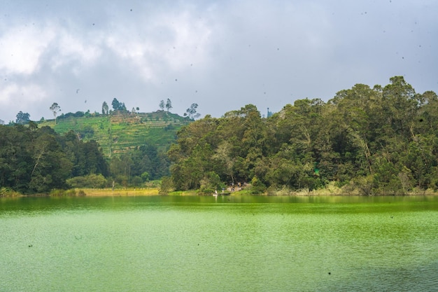 Telaga warna a mystical lake in dieng indonesia changes hues like a chameleon its emerald waters reflect the surrounding forest creating a breathtaking spectacle