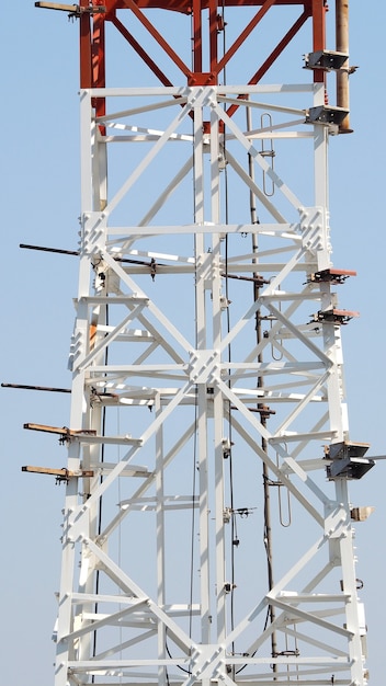 Telecom tower closeup with white color and blue sky.