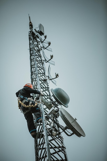 Photo telecom worker climbing antenna tower