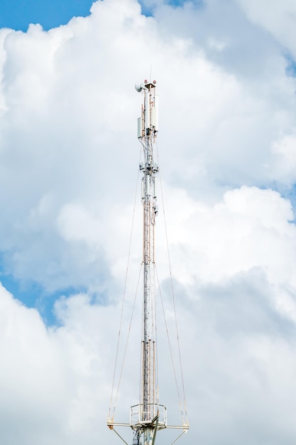 Telecommunicatietoren van 4G en 5G cellulair Macro Base Station 5G radionetwerk telecommunicatieapparatuur met radiomodules en slimme antennes gemonteerd op een metaal tegen de hemelachtergrond van wolken