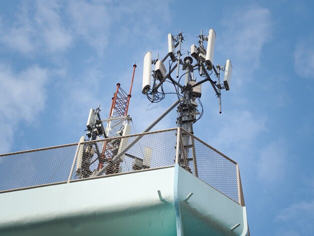 Telecommunication tower against the blue sky with clouds.