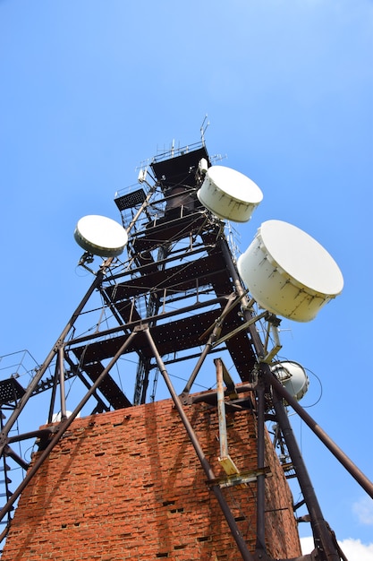 Photo telecommunication tower with antennas on a background of blue sky and clouds. smart antennas transmit 4g and 5g cellular signals to consumers. bottom view