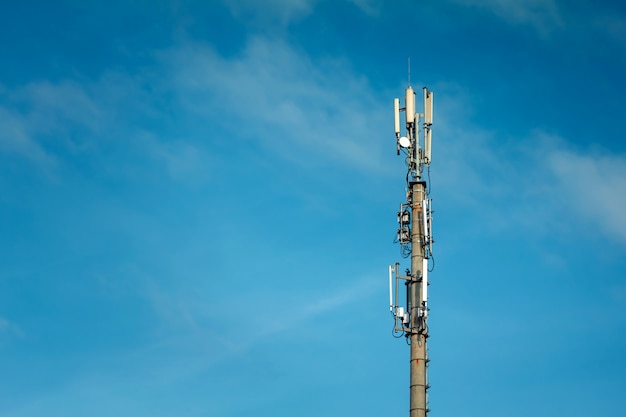 Telecommunications mast set against blue sky and big white cloud