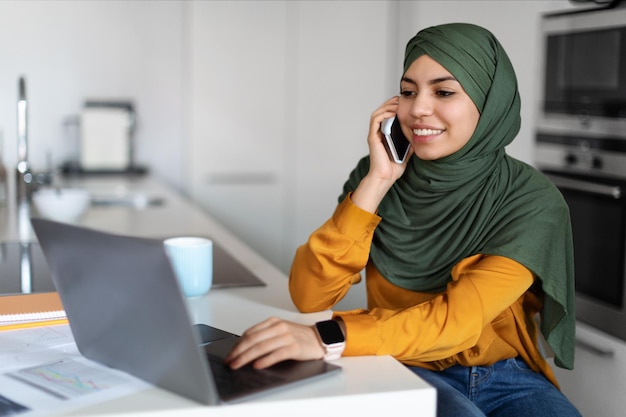 랩톱을 사용 하 고 집에서 핸드폰에 대 한 이야기 Hijab에서 재택 근무 여성
