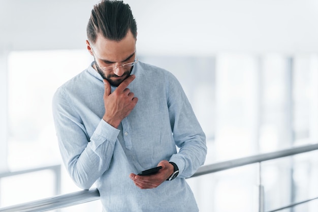 Telefoon gebruiken Jonge knappe man in formele kleding binnenshuis op kantoor overdag