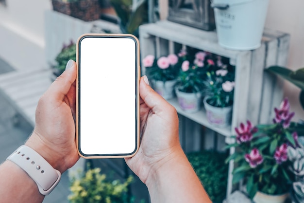 Telefoon in handen met een geïsoleerd scherm op de achtergrond van een bloemenwinkel