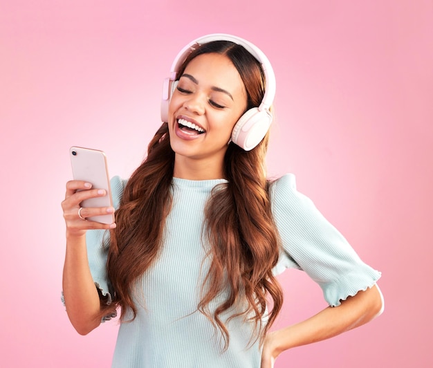 Telefoon muziek koptelefoon en vrouw zingen in studio geïsoleerd op een roze achtergrond Mobiel radio zanger en gelukkige vrouw met mobiele streaming lachen en luisteren naar audio geluid of podcast