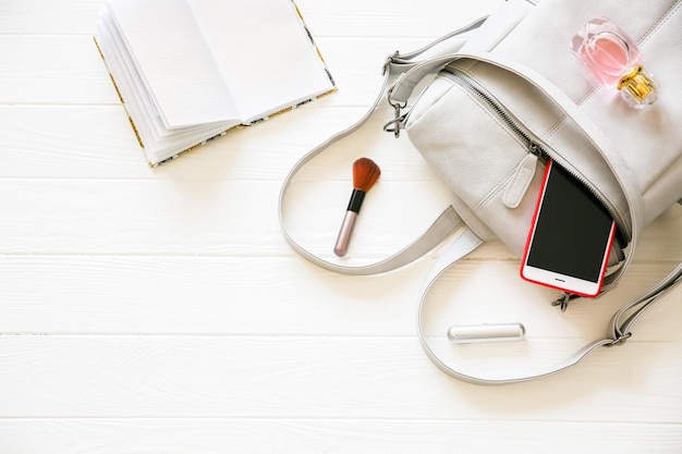 Telefoon stijlvolle tas en parfums op witte achtergrond Mooie plat lag dingen voor zakenvrouw Opmerking boek schema Make-up kit