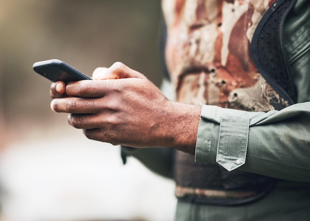 Telefooncamouflage en soldaat in oorlog op sociale media of browsen op internet-app of website bij militair of leger Handen vechten en sms'en op slagveldcompetitie of match met game-veiligheidsuitrusting