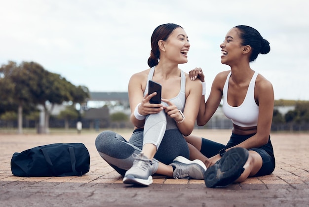 Telefoonfitness en vrouwen op sociale media in de stad Londen na samen trainen op straat Gelukkige glimlach en gezonde atletenvrienden met grappige mobiele app op technologie na buiten trainen