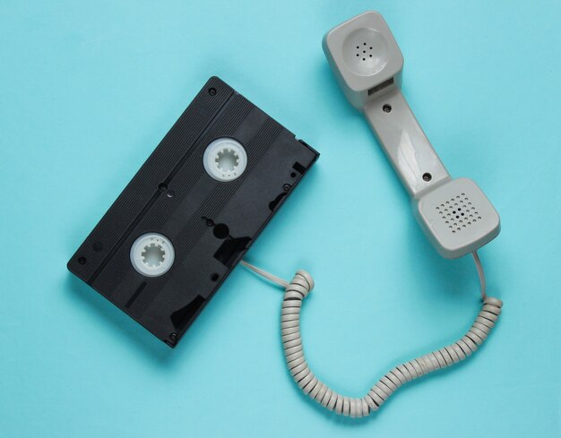 Telefoonhoorn en videocassette op blauw papier