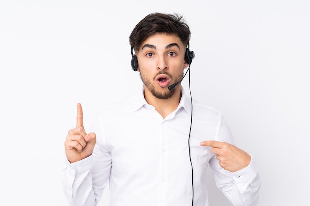 Telemarketeer arabische man aan het werk met een hoofdtelefoon geïsoleerd op wit met verrassende gezichtsuitdrukking