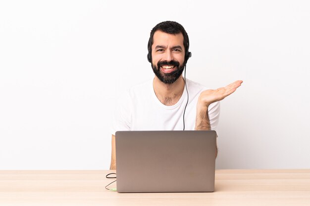 Telemarketeer blanke man aan het werk met een headset en met laptop die copyspace denkbeeldig op de handpalm houdt om een advertentie in te voegen.