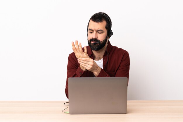 Telemarketeer blanke man aan het werk met een headset en met laptop die lijden aan pijn in handen