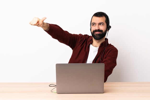 Telemarketeer blanke man aan het werk met een headset en met laptop met een duim omhoog gebaar.