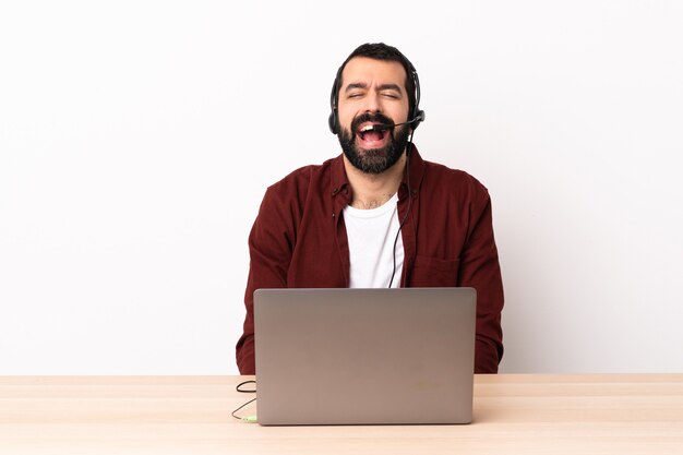 Telemarketeer blanke man aan het werk met een headset en met laptop schreeuwen naar voren met wijd open mond.