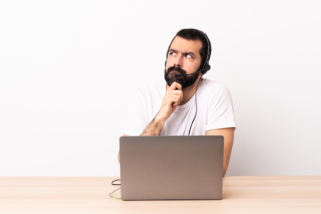 Telemarketeer blanke man aan het werk met een headset en met laptop twijfels en denken.