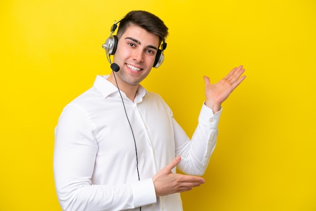 Telemarketeer blanke man aan het werk met een headset geïsoleerd op een gele achtergrond die zijn handen naar de zijkant uitstrekt om uit te nodigen om te komen