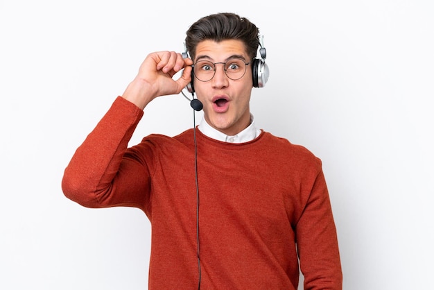 Telemarketeer blanke man aan het werk met een headset geïsoleerd op een witte achtergrond met een bril en verrast