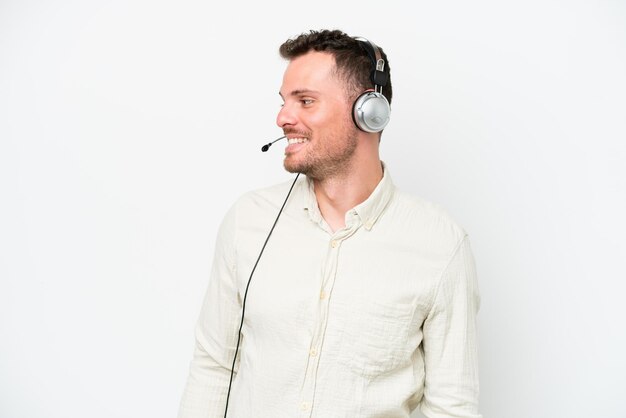 Telemarketeer blanke man aan het werk met een headset geïsoleerd op een witte achtergrond op zoek naar de zijkant