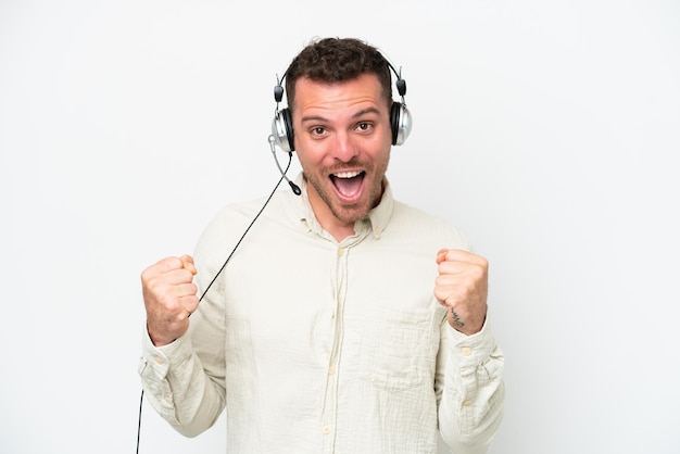 Telemarketeer blanke man aan het werk met een headset geïsoleerd op een witte achtergrond vieren een overwinning in winnaar positie