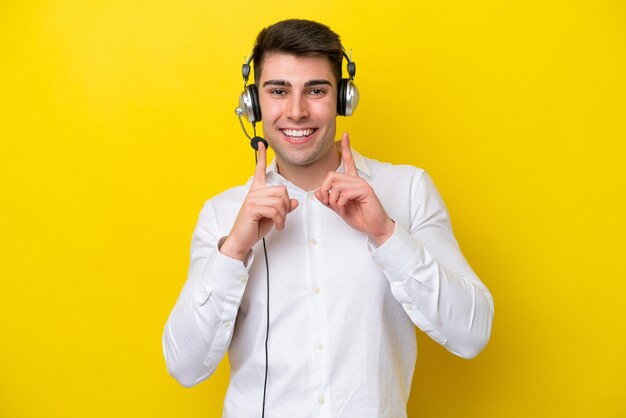 Telemarketeer blanke man aan het werk met een headset geïsoleerd op gele achtergrond glimlachend met een vrolijke en aangename uitdrukking