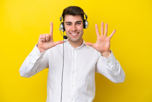 Telemarketeer blanke man aan het werk met een headset geïsoleerd op gele achtergrond zeven tellen met vingers