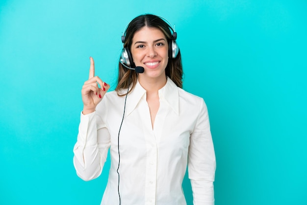 Telemarketeer Italiaanse vrouw die werkt met een headset geïsoleerd op blauwe achtergrond wijzend met de wijsvinger een geweldig idee