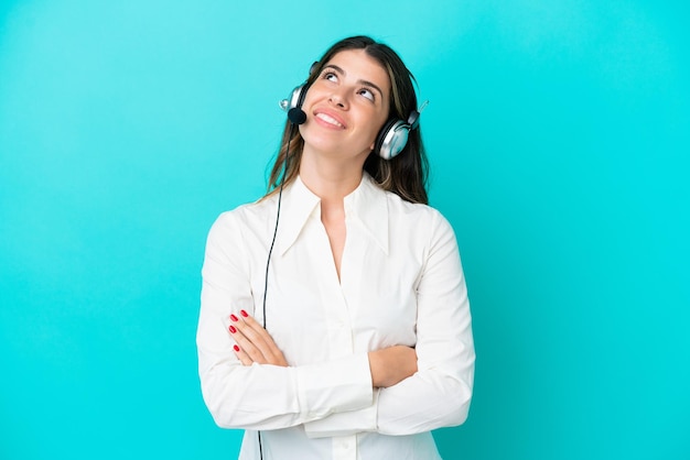 Telemarketeer Italiaanse vrouw die werkt met een headset geïsoleerd op een blauwe achtergrond terwijl ze glimlacht