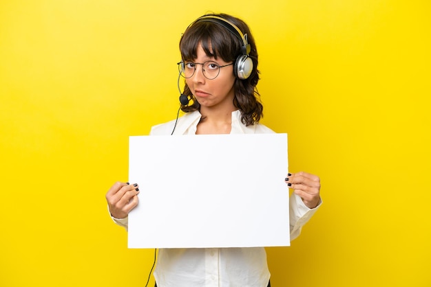 Telemarketeer latijnse vrouw die werkt met een headset geïsoleerd op gele achtergrond met een leeg bordje